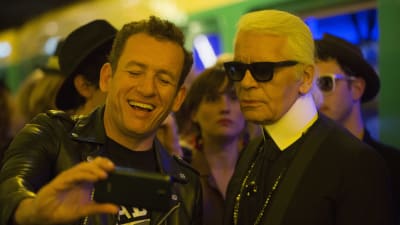 Jean-Rene (Dany Boon) tar en selfie tillsammans med Karl Lagerfeld.