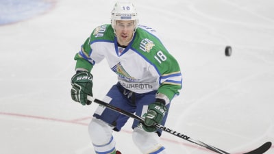 Grön- och vitklädd ishockeyback tar emot studsande puck.