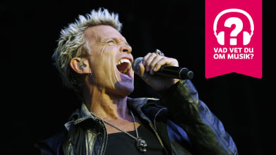 Billy Idol sjunger i en mikrofon som han håller i handen.