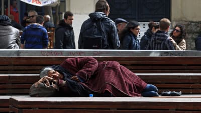 Hemlös kvinna sover på en bänk i Aten, Grekland 6.3.2015.