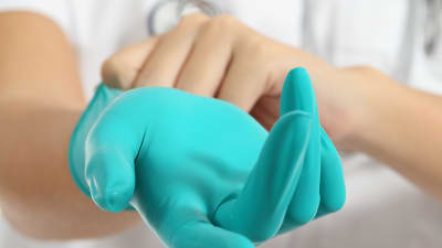 En sjukskötare tar på sig plasthandskar.