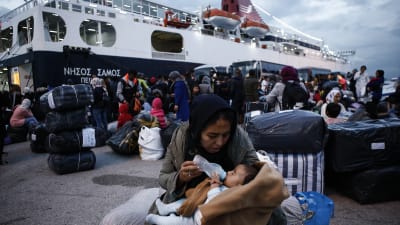 En kvinna matar sin baby efter att ha kommit i land från färjan Nissos Samos som tagit dem från ön Lesbos till hamnen i Pireus, Grekland  7.10.2019