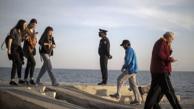 En polis i skyddsmask övervakade flanörer vid en strand utanför Aten på lördagen. 