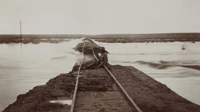 En man sitter på en översvämmad järnväg mellan Keetmanshoop och Lüderitz i dåvarande Tyska Sydvästafrika, nuvarande södra Namibia. Bilden är tagen omkring 1910.