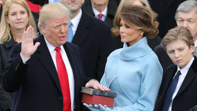 Donald Trump svär presidenteden med handen på två biblar som Melanie Trump håller.