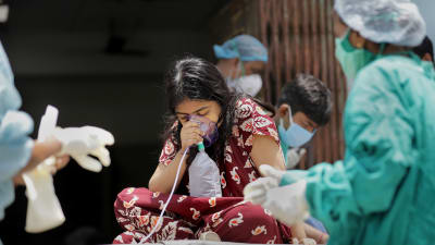 Sjukvårdspersonal i skyddsdräkter ger en indisk kvinna tilläggssyre.