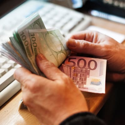 Hand som håller i många eurosedlar.