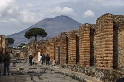 En gata i ruinstaden Pompeji, med vulkanen Vesuvius i bakgrunden.