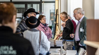 Människor som diskuterar med varandra över bord med böcker