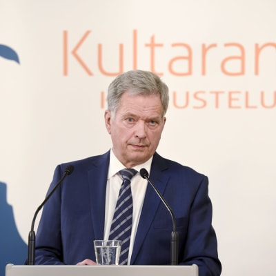 Sauli Niinistö på presskonferens, framför logo för Gullrandasamtalen 