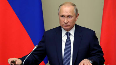 Vladimir Putin vid en talarstol. Ha när iklädd en blå kostym.