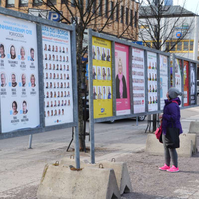 Kvinna studerar valaffischer på trottoar i Borgå.