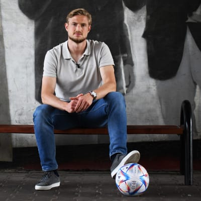 Richard Jensen sitter på en bänk med en fotboll vid fötterna.