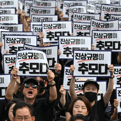 Ihmisillä koreankielisiä plakaatteja mielenosoituksessa