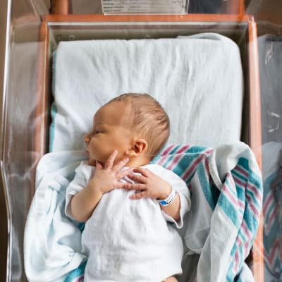 En nyfödd bebis ligger i en sjukhussäng.