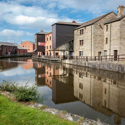 Industriområdet Wigan Pier var ett centrum för den tillverkande industrin i staden. På bilden ser historiska industrianläggningar vid ett vattendrag. 