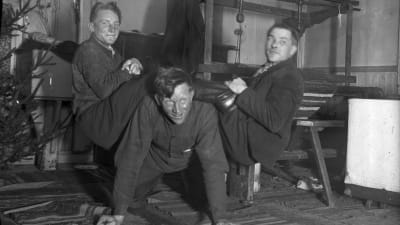 Tre män leker "lyfta saltsäck", där en person är på golvet på alla fyra, och två andra är på den förstas rygg medan han försöker stiga upp. Bilden är tagen 1935 i Bromarf.