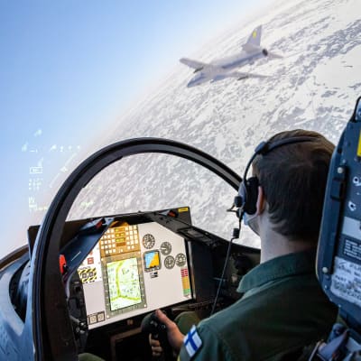 Oppilas Hawk-lentosimulaattorin ohjaimissa Ilmasotakoulussa Tikkakoskella. Kuvaruudulla näkyy oikeasti ilmassa oleva Hawk-hävittäjä.
