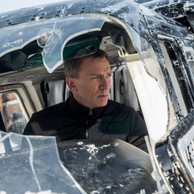 Bond istuu lentokoneessa, jonka ikkuna on rikki.