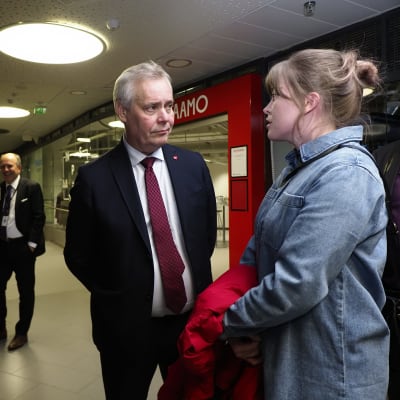 Minister Antti Rinne i mitten lyssnar på en kvinna till höger.