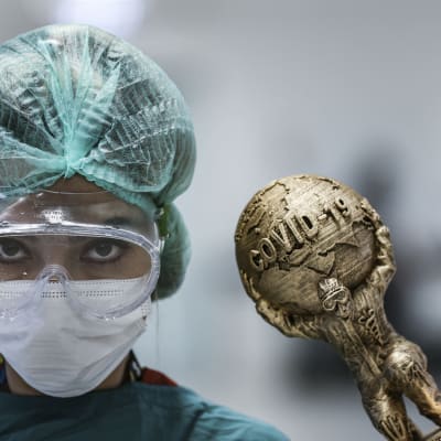 Turkkilainen sairaanhoitaja ja koronapandemian taakkaa symboloiva pienikokoinen patsas