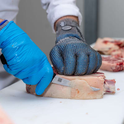 Dry Aged lihaa leikataan. Leikkaajalla kädessä metallinen suojahansikas ja kuihanskat.
