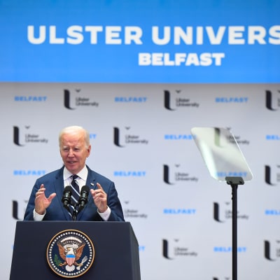 USA:s president Joe Biden gestikulerar under sitt tal vid Ulster University i Nordirland. På en skylt bakom honom står det Ulster University Belfast.
