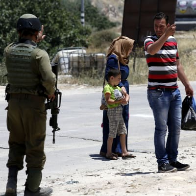En palestinsk familj vid en israelisk vägspärr på Västbanken torsdagen 9.6.2016