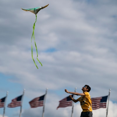 En pojke flyger drake. I bakgrunden syns USA:s flaggor.
