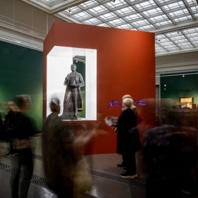 Näyttelyvieraita Albert Edelfeltin valaistun patsaan ympärillä Ateneumin taidemuseossa.