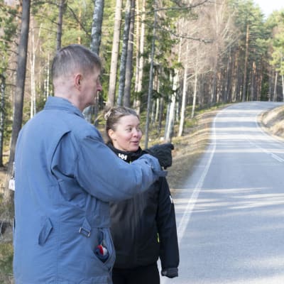 Två mänskor vid en väg, mannen pekar över vägen
