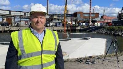 Hitachi Energyn Vaasan muuntajatehtaan liiketoimintajohtaja Toni Koskinen seisoo Vaasan satamassa. Taustalla upotetaan laitteen avulla veteen suurta muuntajaa.