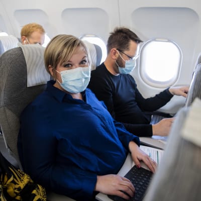 Kuvassa lentokoneessa maskit kasvoillaan ovat Annika Saarikko ja Erkki Papunen.