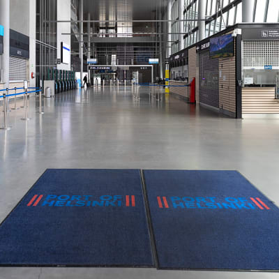 Dörrarna öppnas till en tom färjeterminal med två stora blå mattor på golvet, där det står Port of Helsinki.