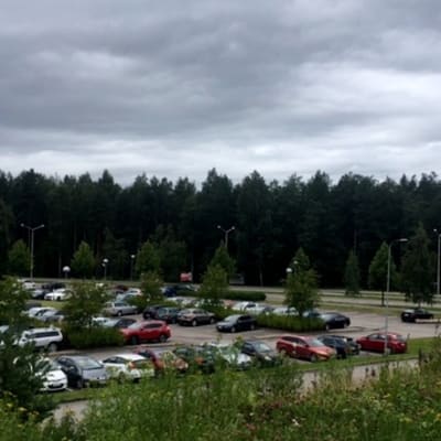 Kouvolan oikeus- ja poliisitalon parkkipaikalla autoja, parkkipaikan takana metsä, jonne sairaalahenke Ratamo-keskus Kouvolassa suunniteltu