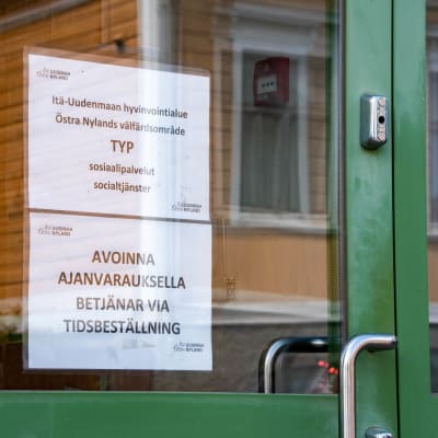 Lappar på en dörr där det står "Östra Nylands välfärdsområde TYP socialtjänster".