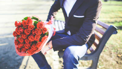 Man med röda rosor på en bänk.