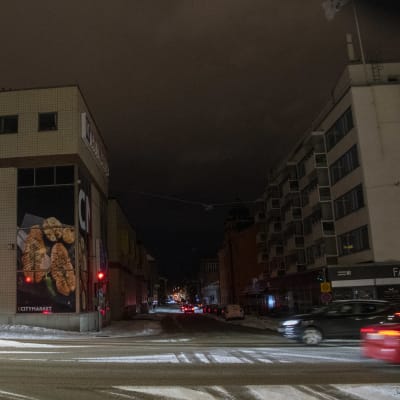 En mörk gata i Borgå centrum, bara bilarnas ljus lyser upp kvällen.