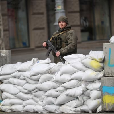 Ukrainalainen naissotilas seisoo vartiossa hiekkasäkkien takana. 
