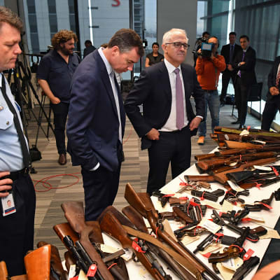Justitieminister Michael Keenan och premiärminister Malcolm Turnbull ser på en del av de över 50 000 vapen som polisen samlade in