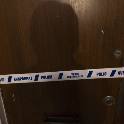 Kuvassa Ullanlinnan henkirikoksen epäillyn tekopaikan, kerrostaloasunnon ulko-ovi. Oven päälle on vedetty poliisiteippiä.