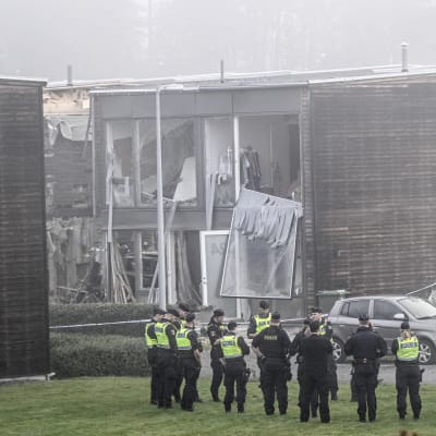 Poliser står utanför bostadshus som skadats i ett sprängdåd i Fullerö norr om Uppsala. En ung kvinna omkom i explosionen tidigt på morgonen den 28 september.