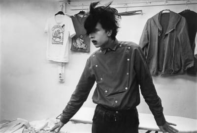 Kaidena tunnettu artisti nuoruudessaan 1979 Lepakko-yökerhossa, t-paitoja seinällä takana.