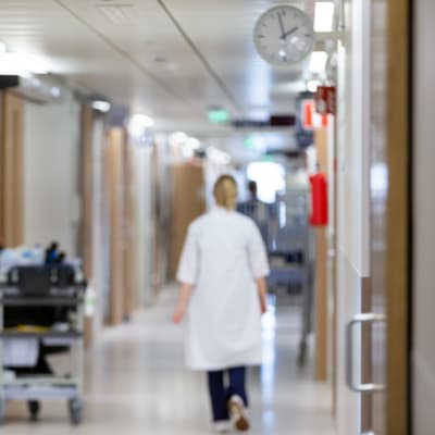 En sjukskötare går genom sjukhuskorridor.
