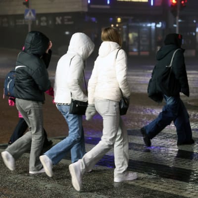 Nuoria ylittämässä katua iltahämärässä Lahden keskustassa, nuoret kuvassa selin suojatiellä ylittämässä katua.