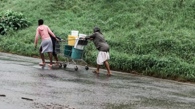 Människor hämtar vatten i Ntuzuma, norr om Durban efter att regn och lerskred orsakat förödelse.