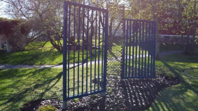 Staket av två fristående träskärmar och en mönstrad, lite rostig metallskärm.
