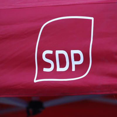 Socialdemokratiska partiets logotyp i vitt på en röd tältduk.