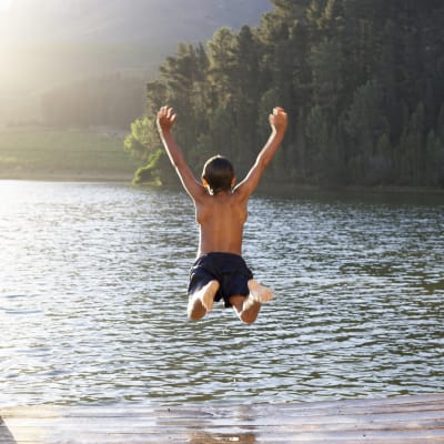 Pojke hoppar i en sjö