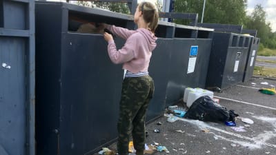 En kvinna sätter in avfall i en behållare vid en sorteringsstation.